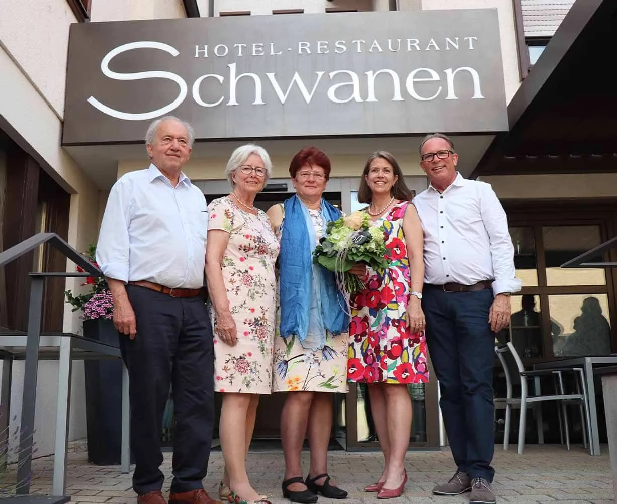 Fünf Personen stehen vor dem Hotel-Restaurant Schwanen Eingang, lächeln und halten Blumenstrauß.